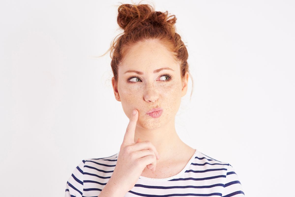 Woman holding finger beside her mouth in a thinking posture.