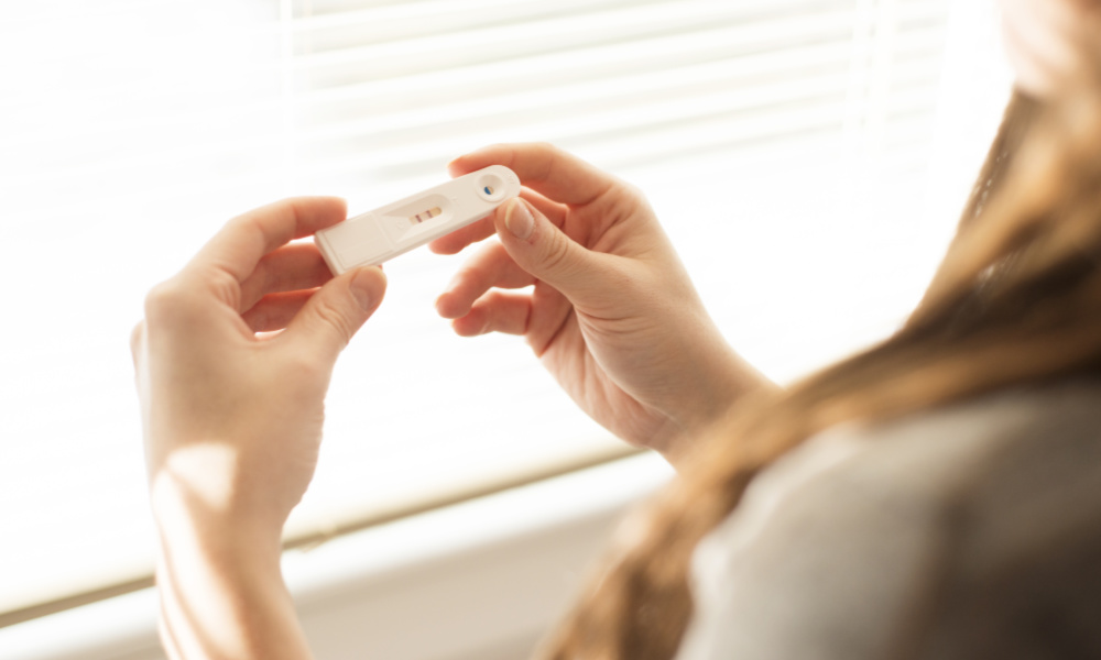 Woman holding positive pregnancy test in her hands.