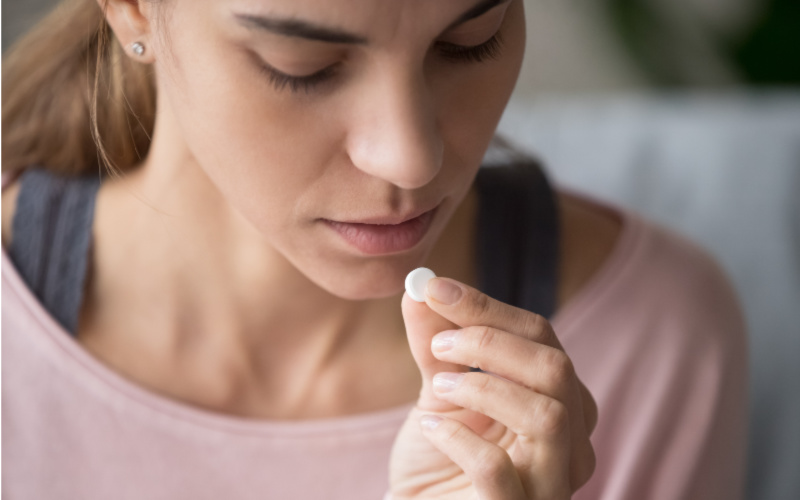 Woman holding pill up to her mouth- concept of taking the abortion pill.