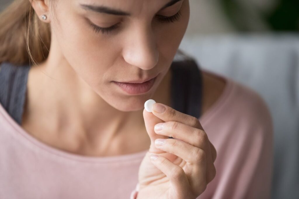 Woman starting to take a pill in her hand.