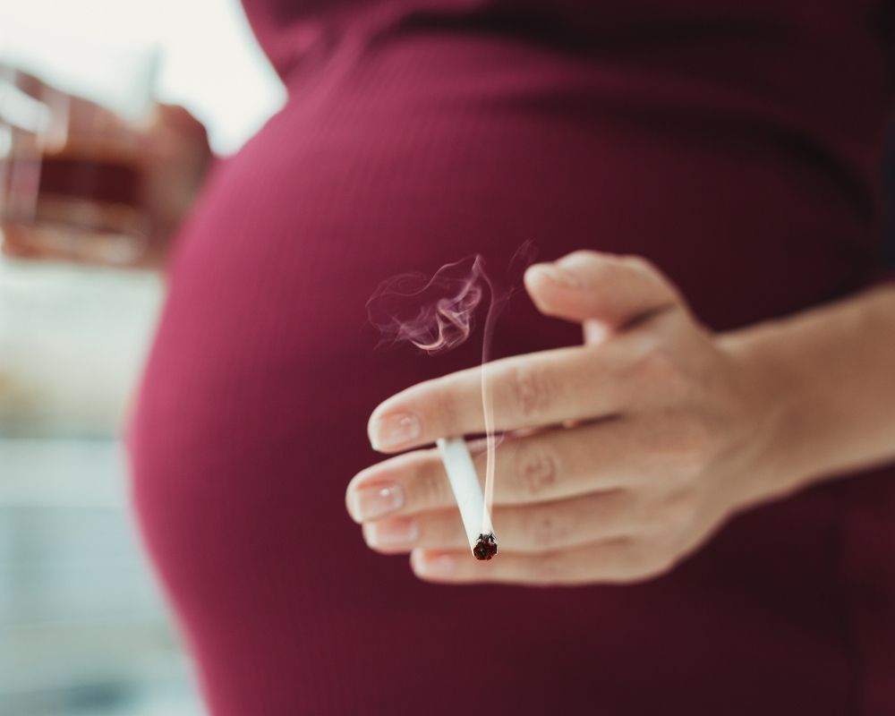 Pregnant women holding cigarette in her hand