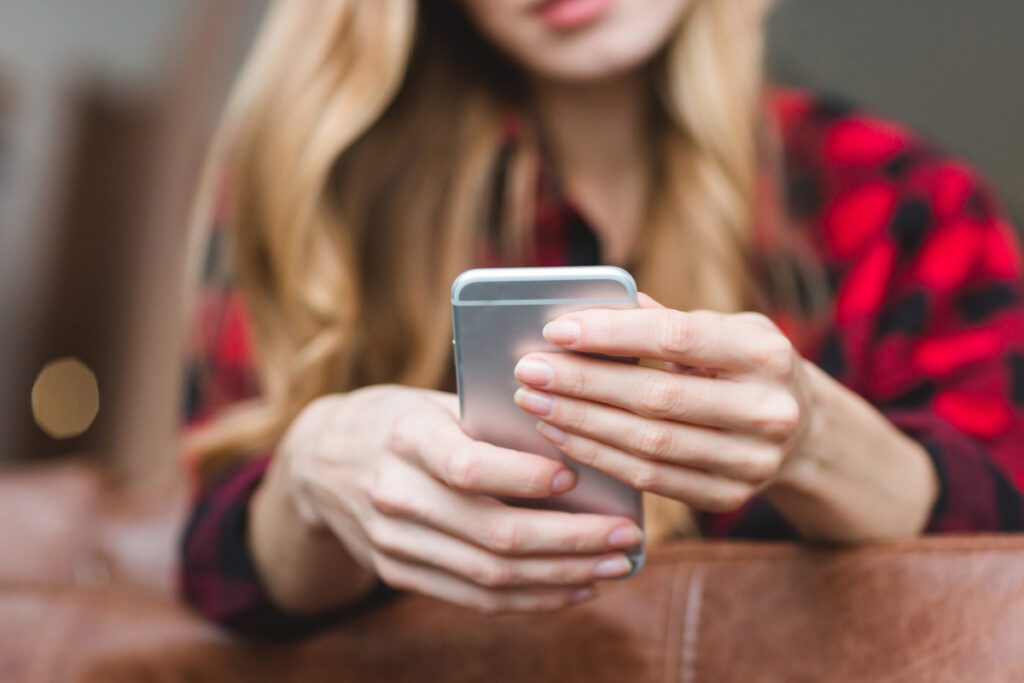 Woman at home holding a smart phone.