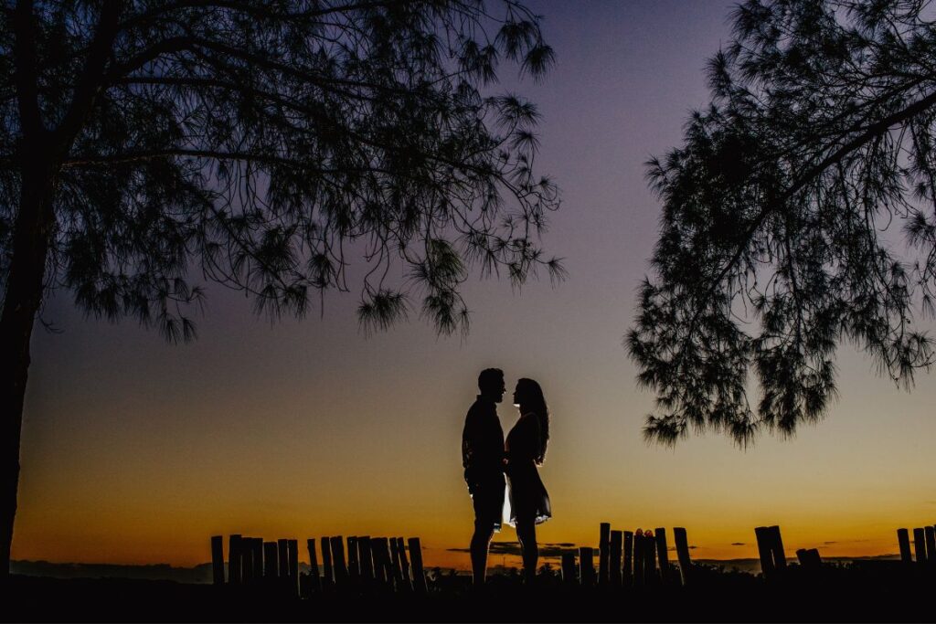 Dating couple standing outside in front of a sunset