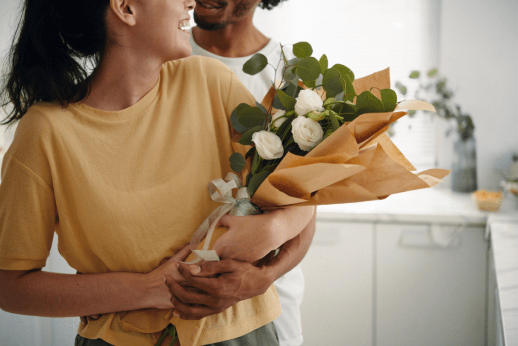 woman holding flowers with dating partner standing behind her smiling