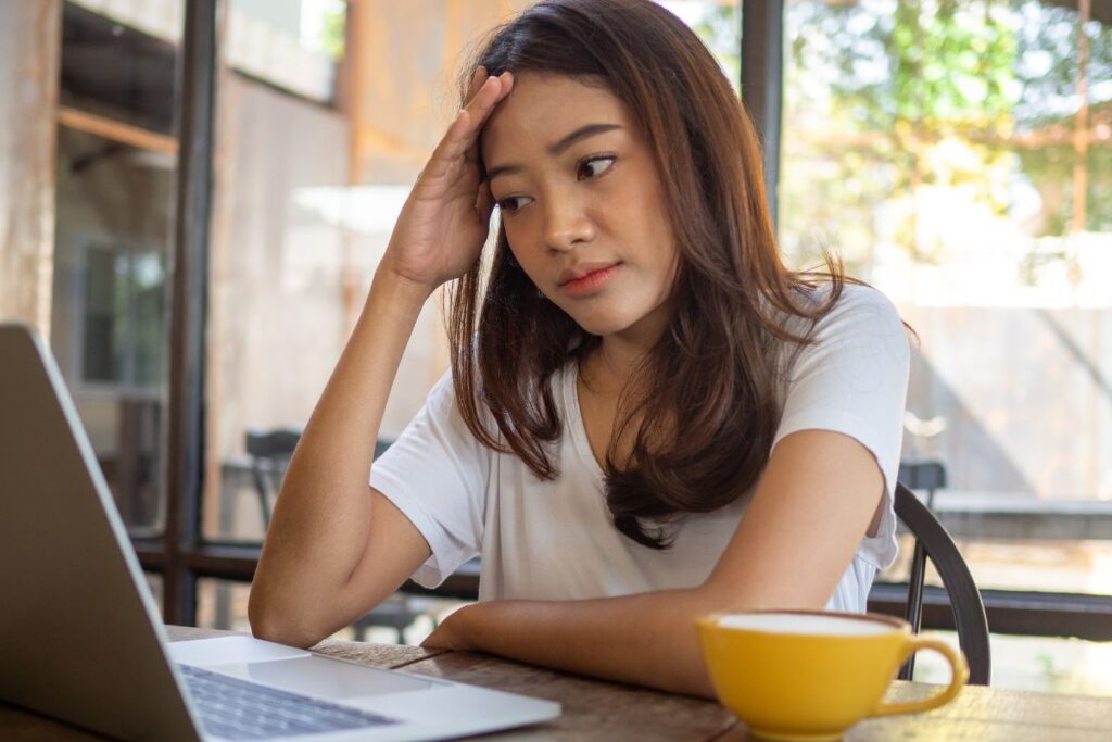 Confused young woman looking at her laptop screen.