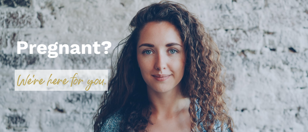 Image of young woman with curly hair standing against white brick wall with text overlay "Pregnant? We're here for you."