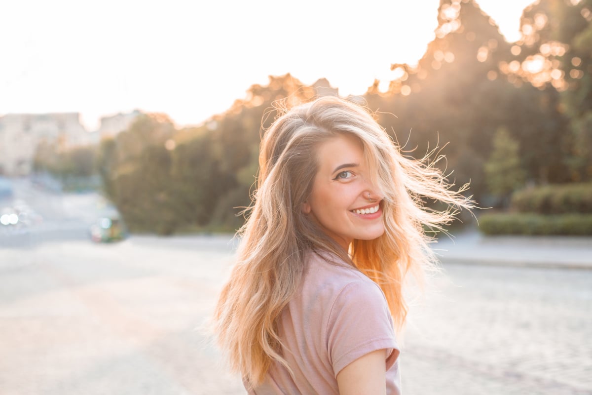 Young blonde woman looking back at camera, smiling