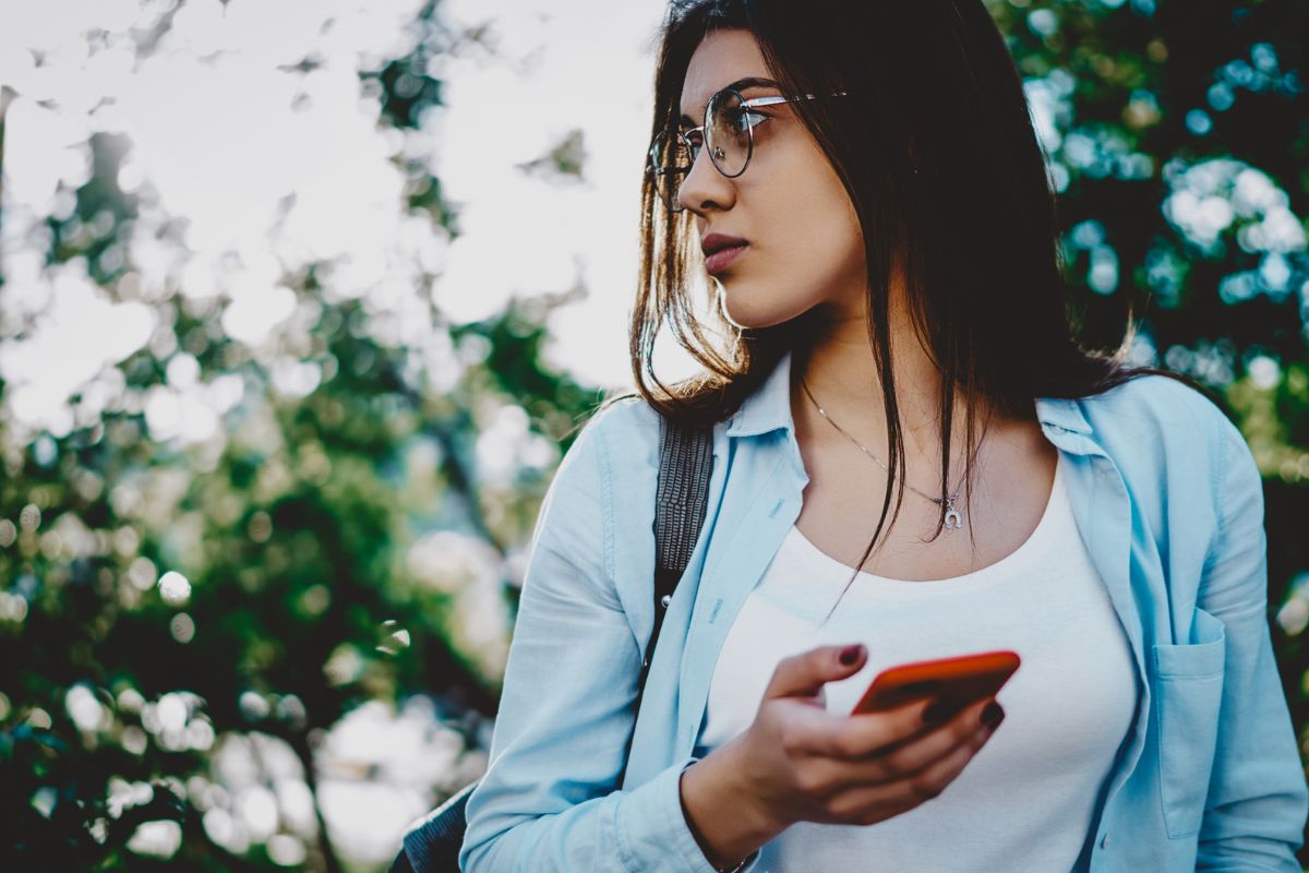 Young woman outdoors holding cell phone