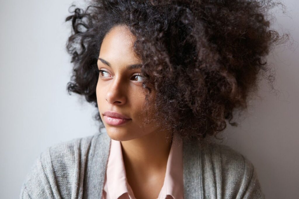 Beautiful African american woman in a button up shirt and sweater, looking into the distance.