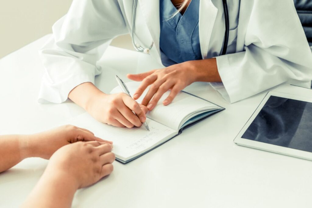Woman consulting with doctor while doctor writes in a notepad.