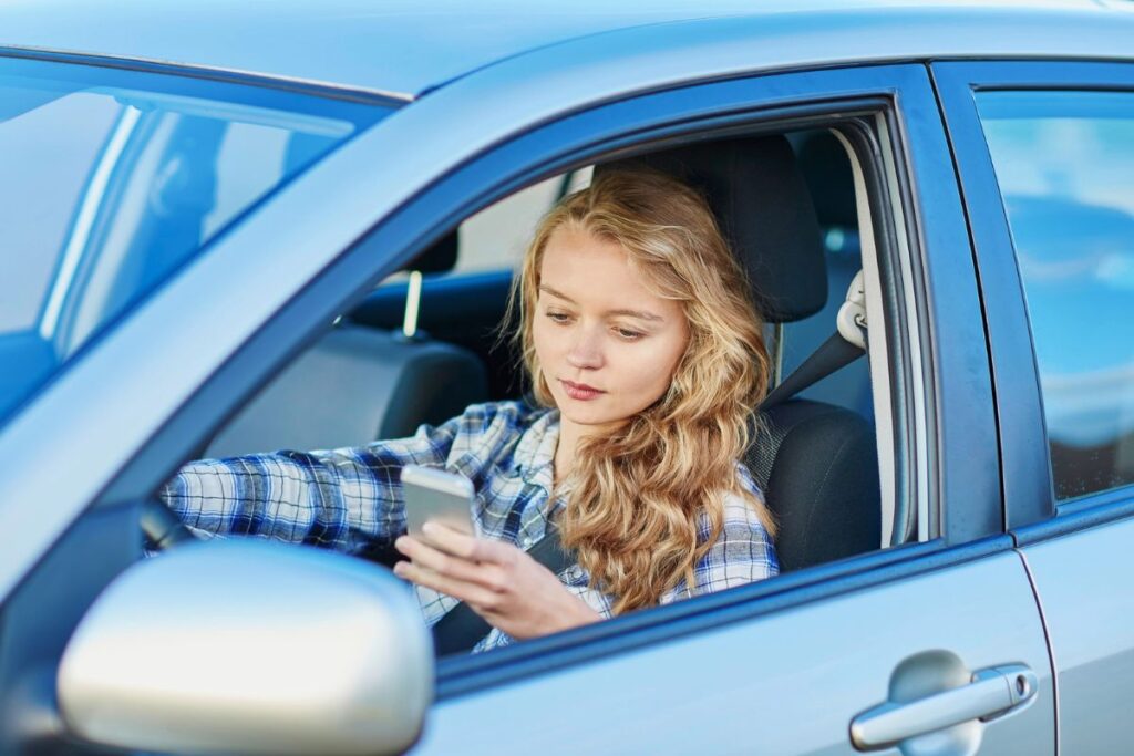 Young woman driving in her car using smartphone for directions.