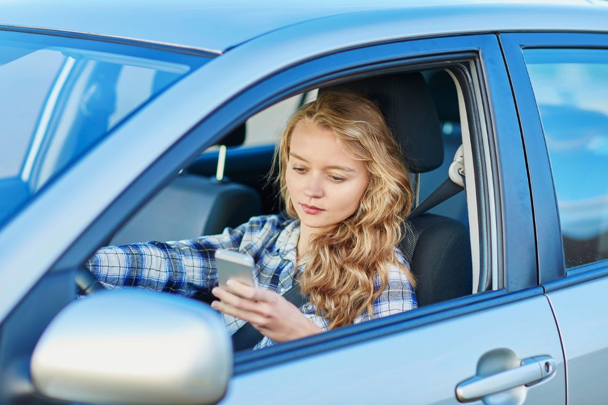 woman in parked car looking at her phone