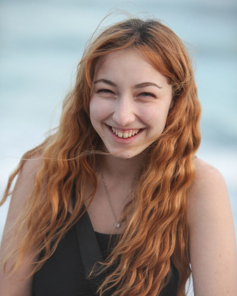 Young woman with long red hair smiling- profile image