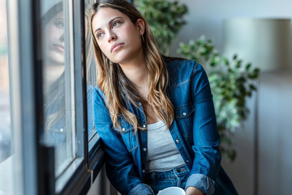 woman leaning against window, thinking
