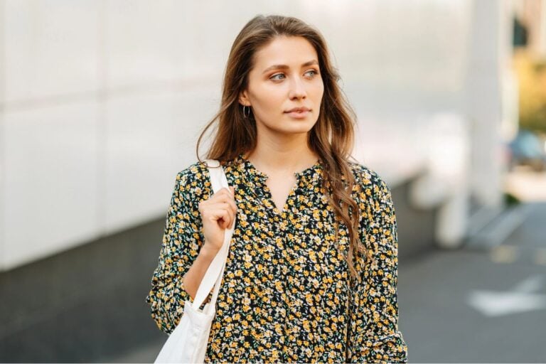 Young woman holding large purse, walking in the city alone.
