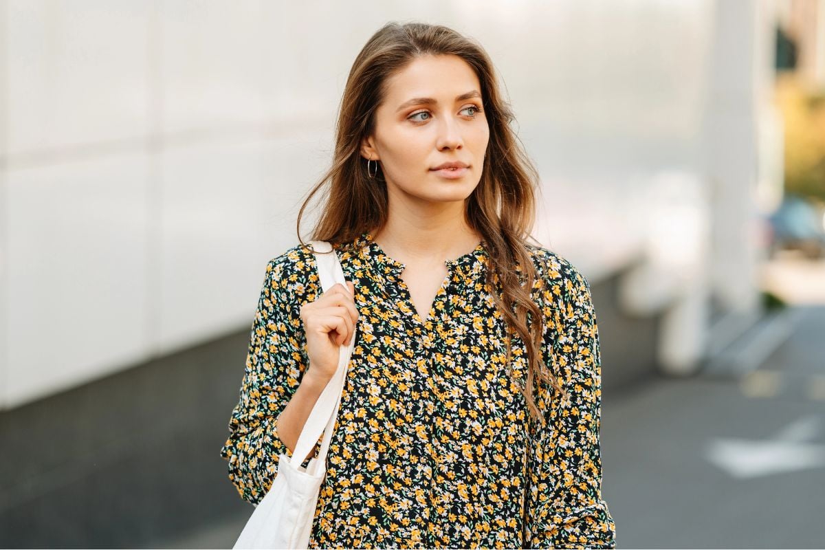 Young woman holding large purse, walking in the city alone.