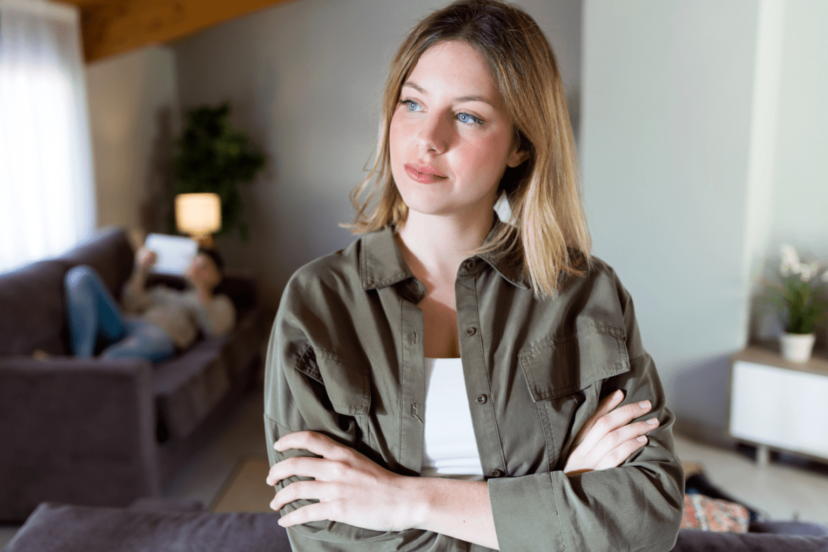 Young blonde woman standing with arms crossed, thinking in her home.